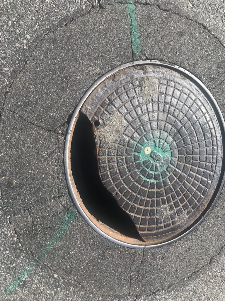 Broken manhole cover illustrating access and safety risks within a municipal wastewater system