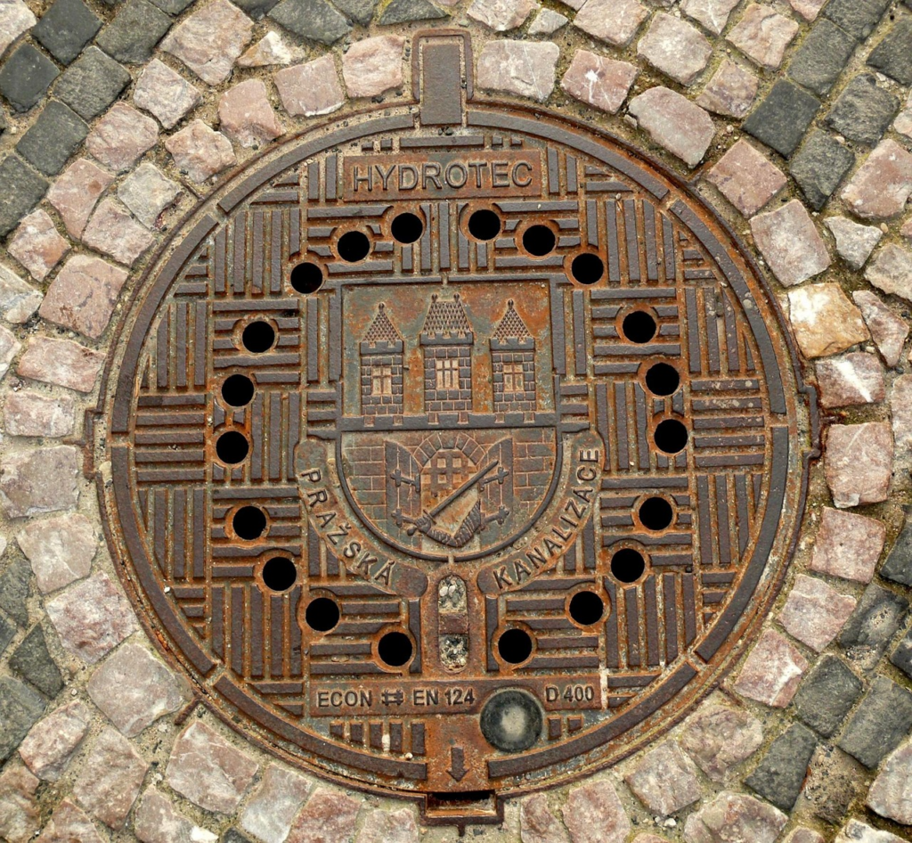 Cast iron manhole cover with vent holes that allow stormwater inflow during wet-weather conditions