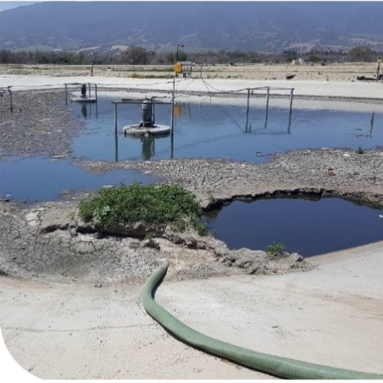 Lagoon aerator operating in a wastewater treatment lagoon with visible dead zones and sludge buildup around the unit.