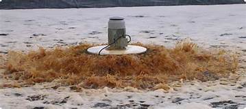 Small floating surface aerator ringed with rags on an iced-over wastewater lagoon.