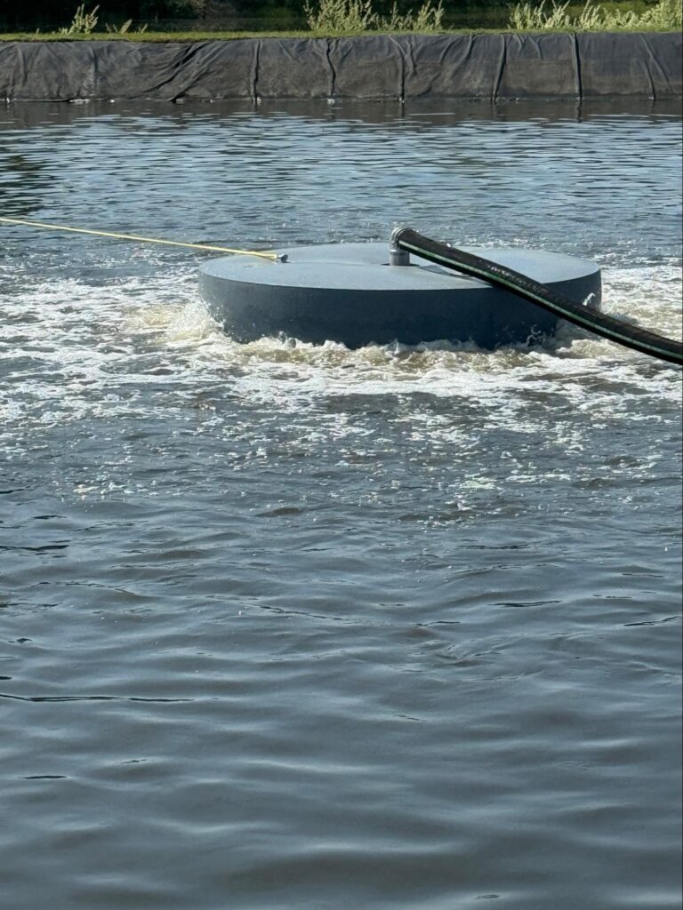 Titus Twister FL floating aerator running in a lined wastewater lagoon with visible surface circulation.